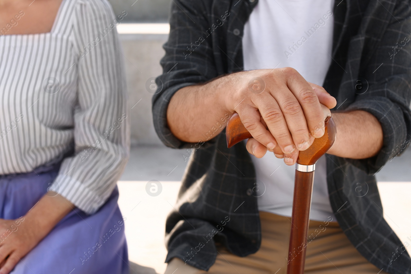 Photo of Couple of pensioners with cane sitting outdoors, closeup