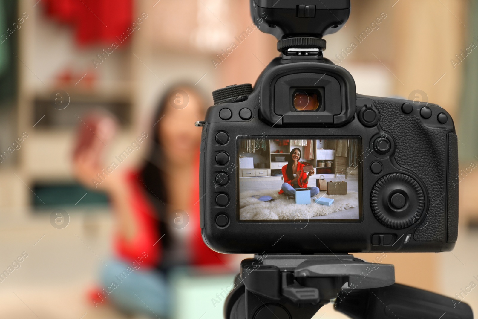 Photo of Fashion blogger recording new video in room, focus on camera