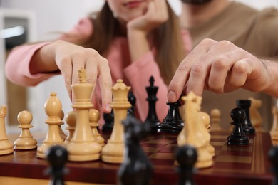 Photo of Father teaching his daughter to play chess, closeup