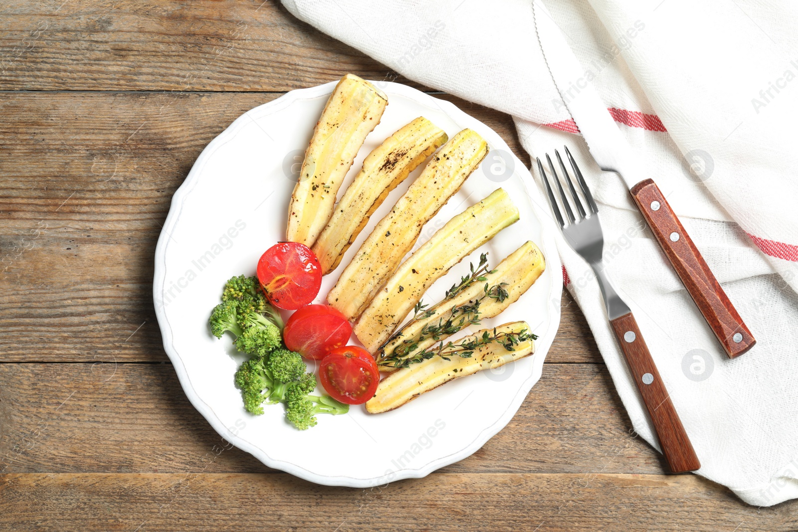 Photo of Baked white carrot served on wooden table, flat lay