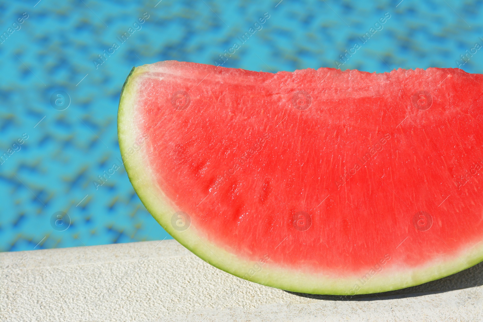 Photo of Slice of fresh juicy watermelon near swimming pool outdoors, closeup