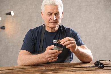 Male jeweler evaluating semi precious gemstone at table in workshop