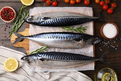 Photo of Raw mackerel, tomatoes and rosemary on wooden table, flat lay