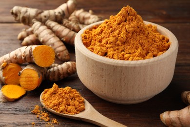 Aromatic turmeric powder and raw roots on wooden table, closeup