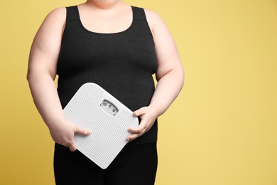 Overweight woman with scales on color background