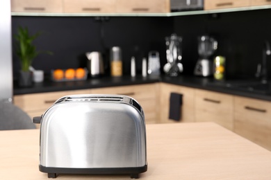 Photo of Modern toaster on table in kitchen, selective focus