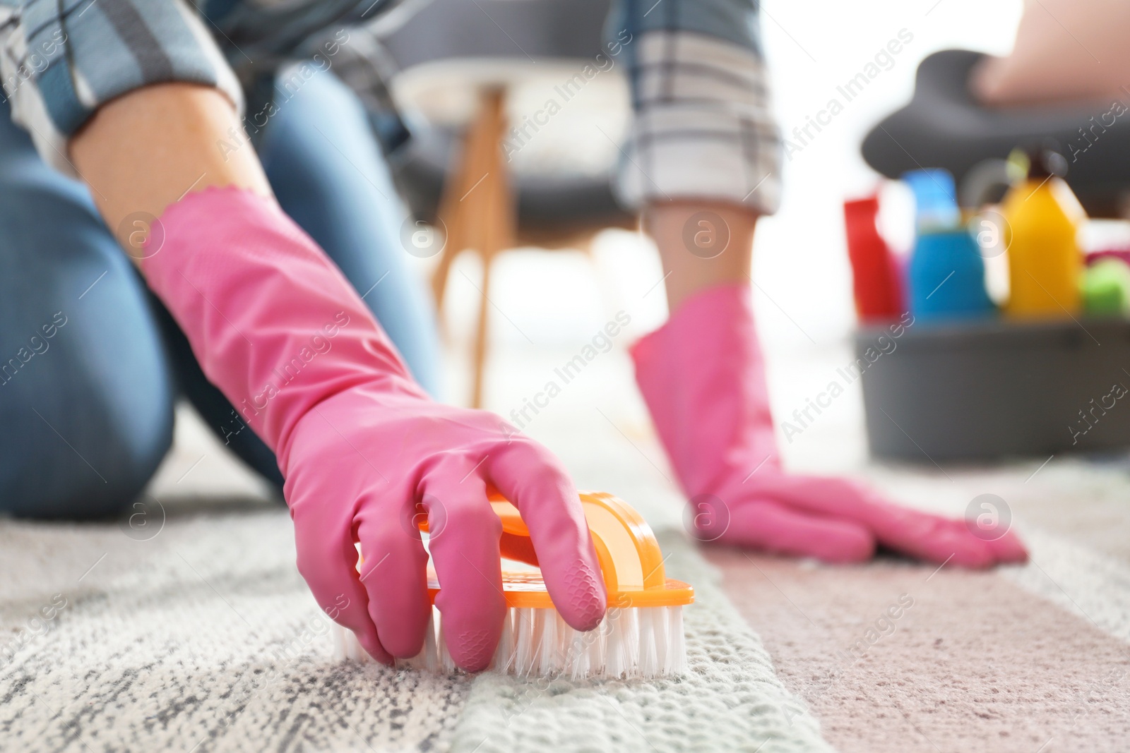 Photo of Woman cleaning carpet with brush in living room, closeup