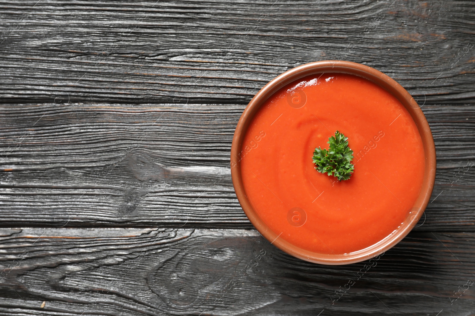 Photo of Bowl with fresh homemade tomato soup and space for text on wooden background, top view