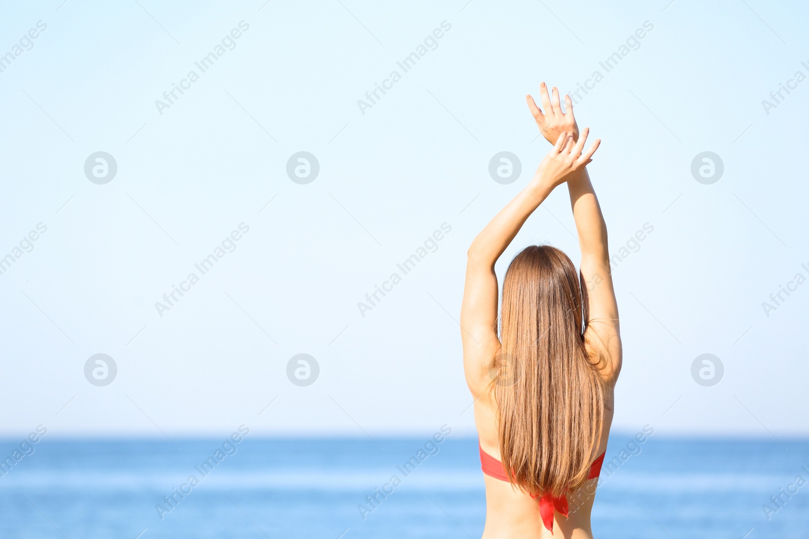 Photo of Young woman in red bikini near sea. Space for text