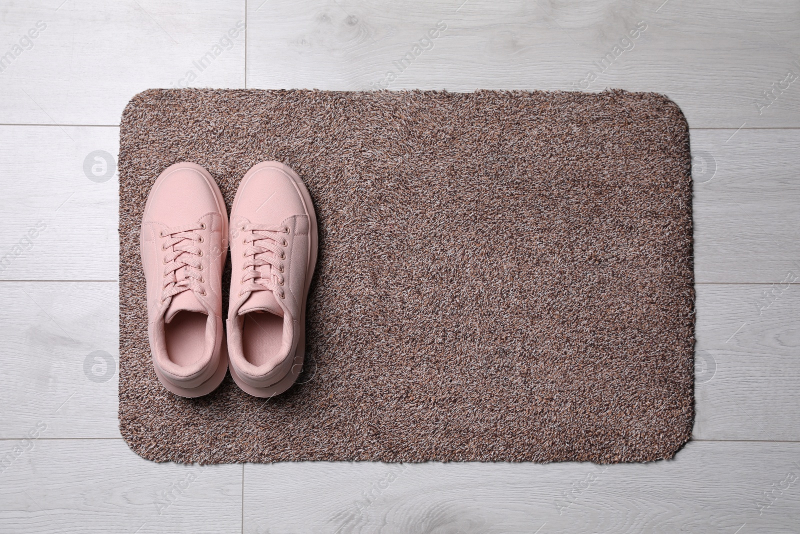 Photo of New clean door mat with shoes on floor, top view