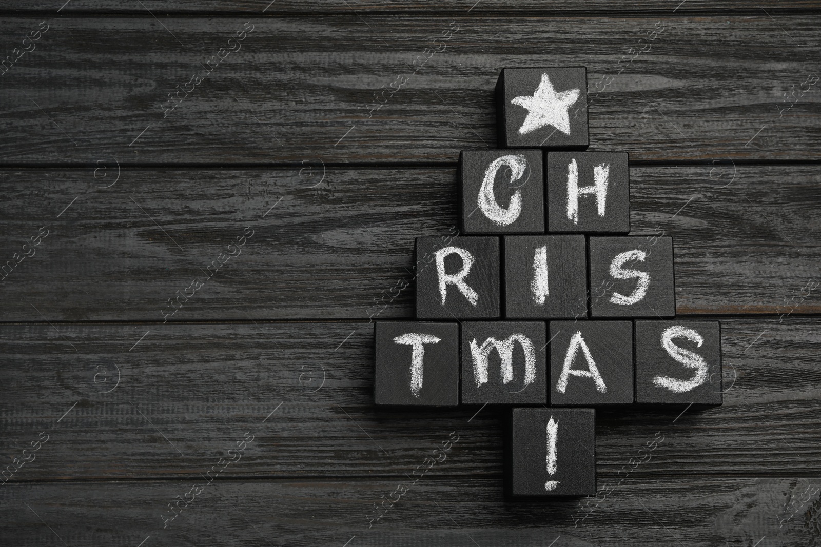 Photo of Christmas tree made of cubes on black wooden background, top view. Space for text