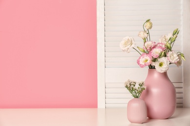 Photo of Beautiful flowers in vases and space for text on color background. Element of interior design