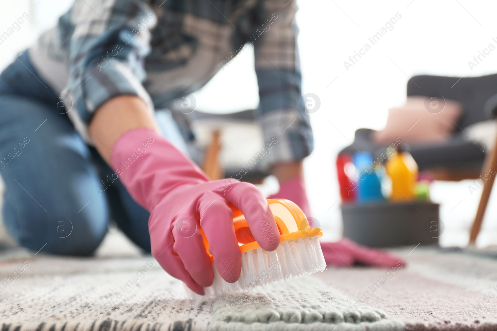 Photo of Woman cleaning carpet with brush in living room, closeup