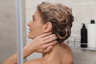 Photo of Beautiful happy woman washing hair with shampoo in shower