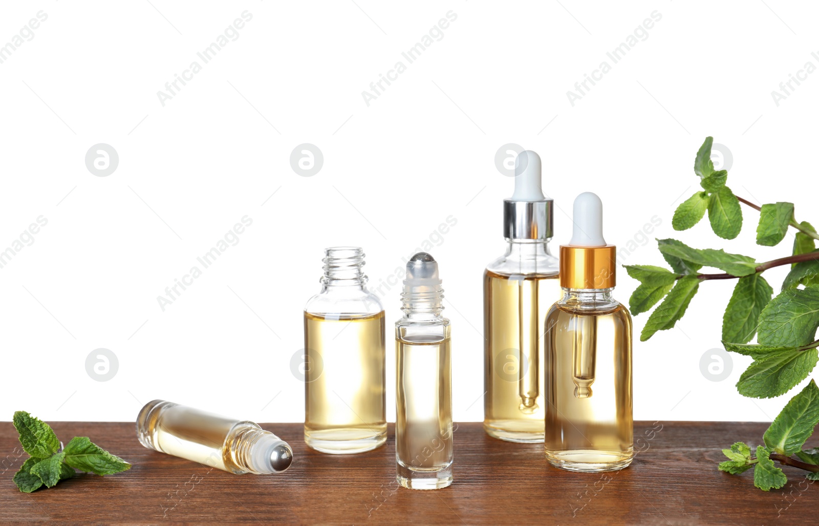 Photo of Bottles of mint essential oil on wooden table against white background. Space for text