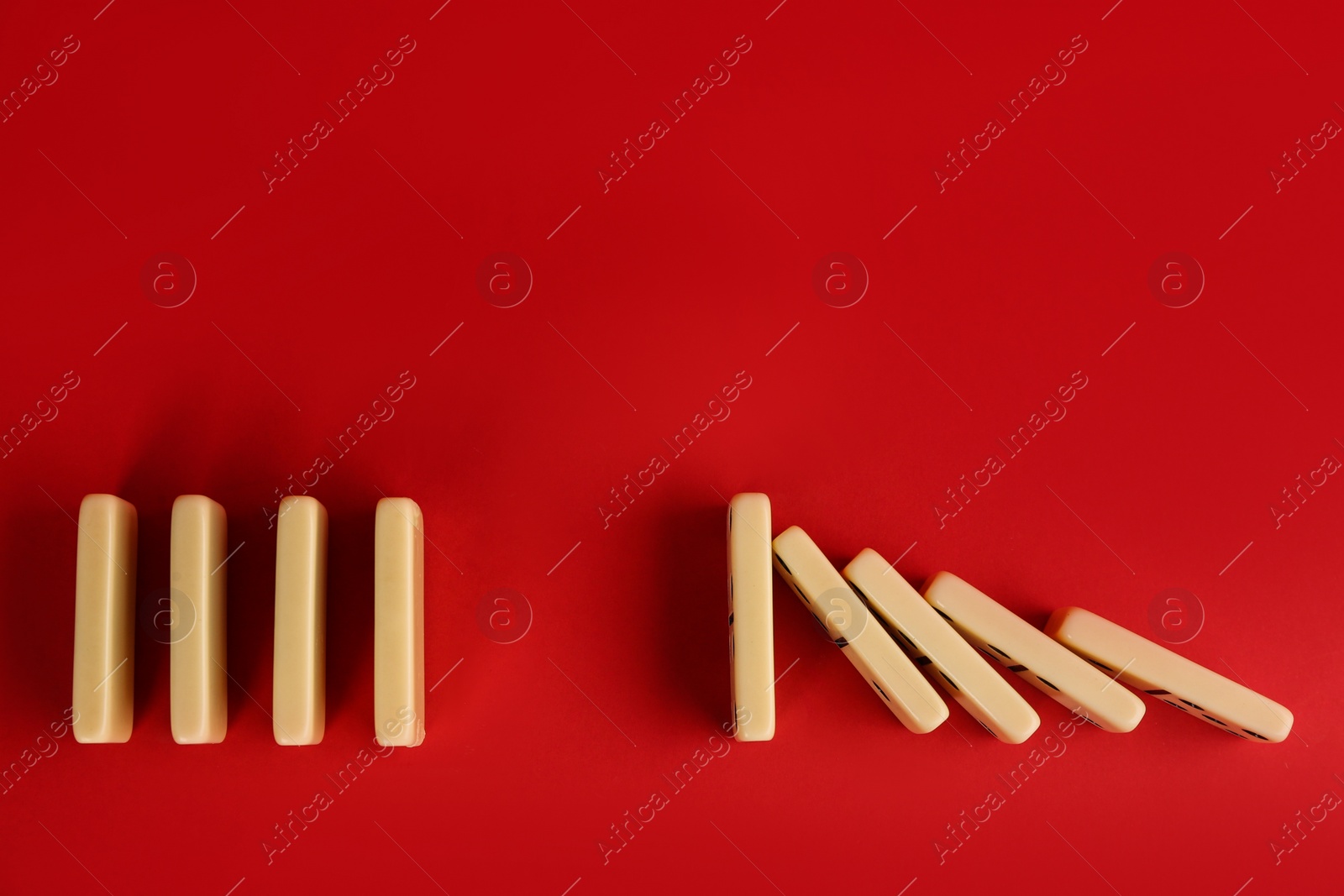 Photo of White domino tiles on red background, flat lay. Space for text
