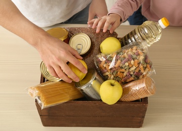 Volunteers taking food out of donation box on table, closeup