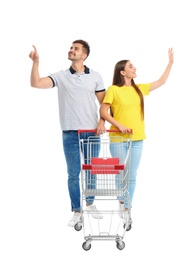 Young couple with empty shopping cart on white background