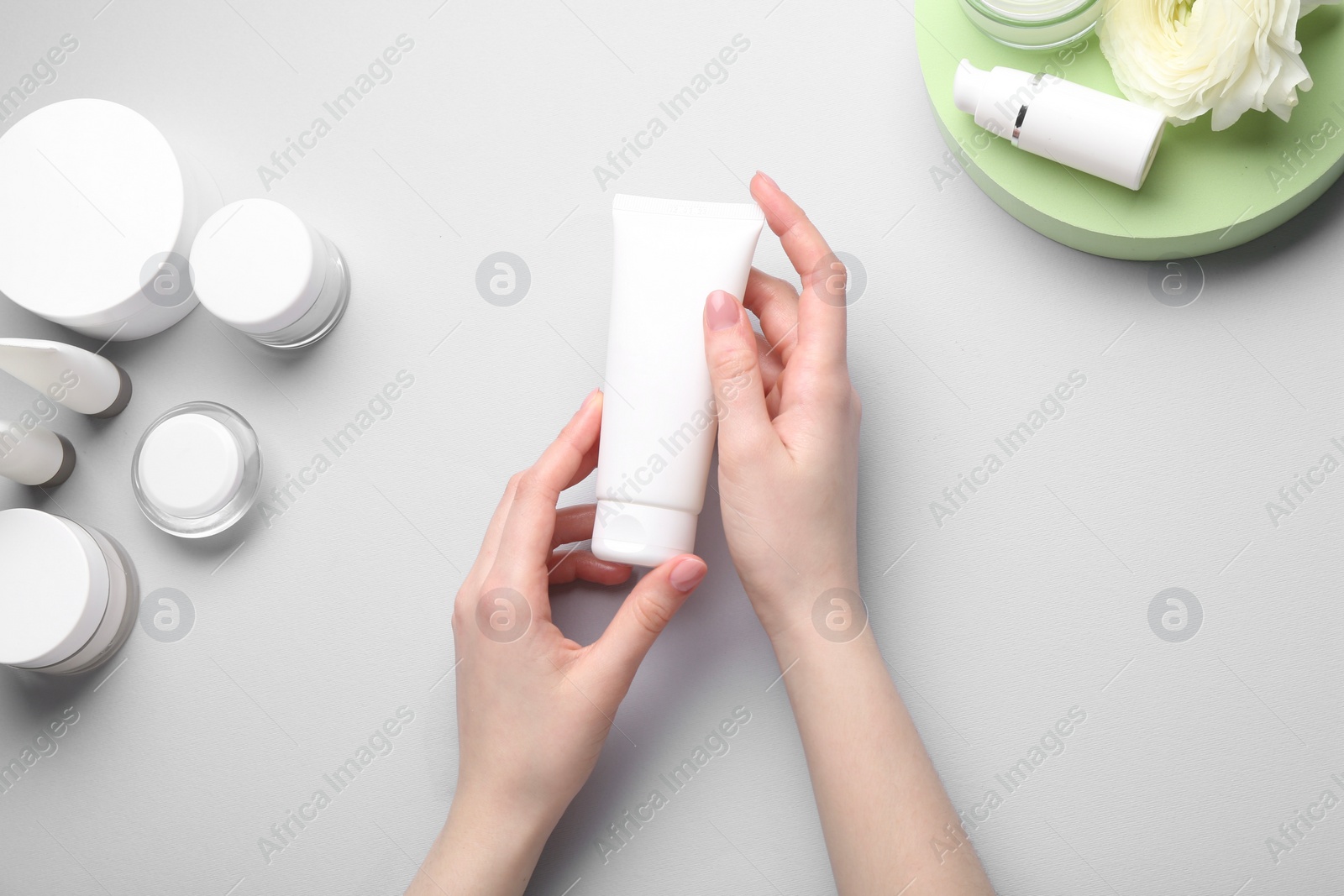 Photo of Woman holding tube of cream on light background, top view