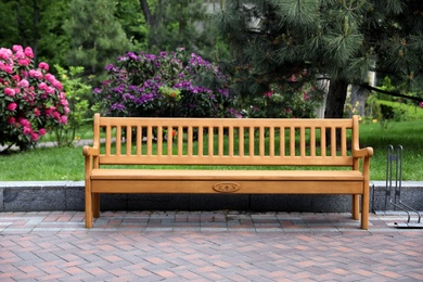 Photo of Comfortable wooden bench in beautiful garden. Place for rest