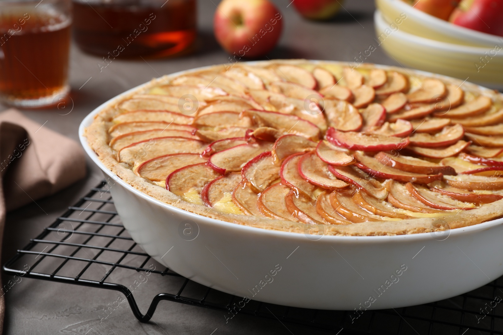 Photo of Tasty apple pie in baking dish on grey table, closeup
