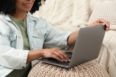 Photo of Woman using laptop on pouf at home, closeup