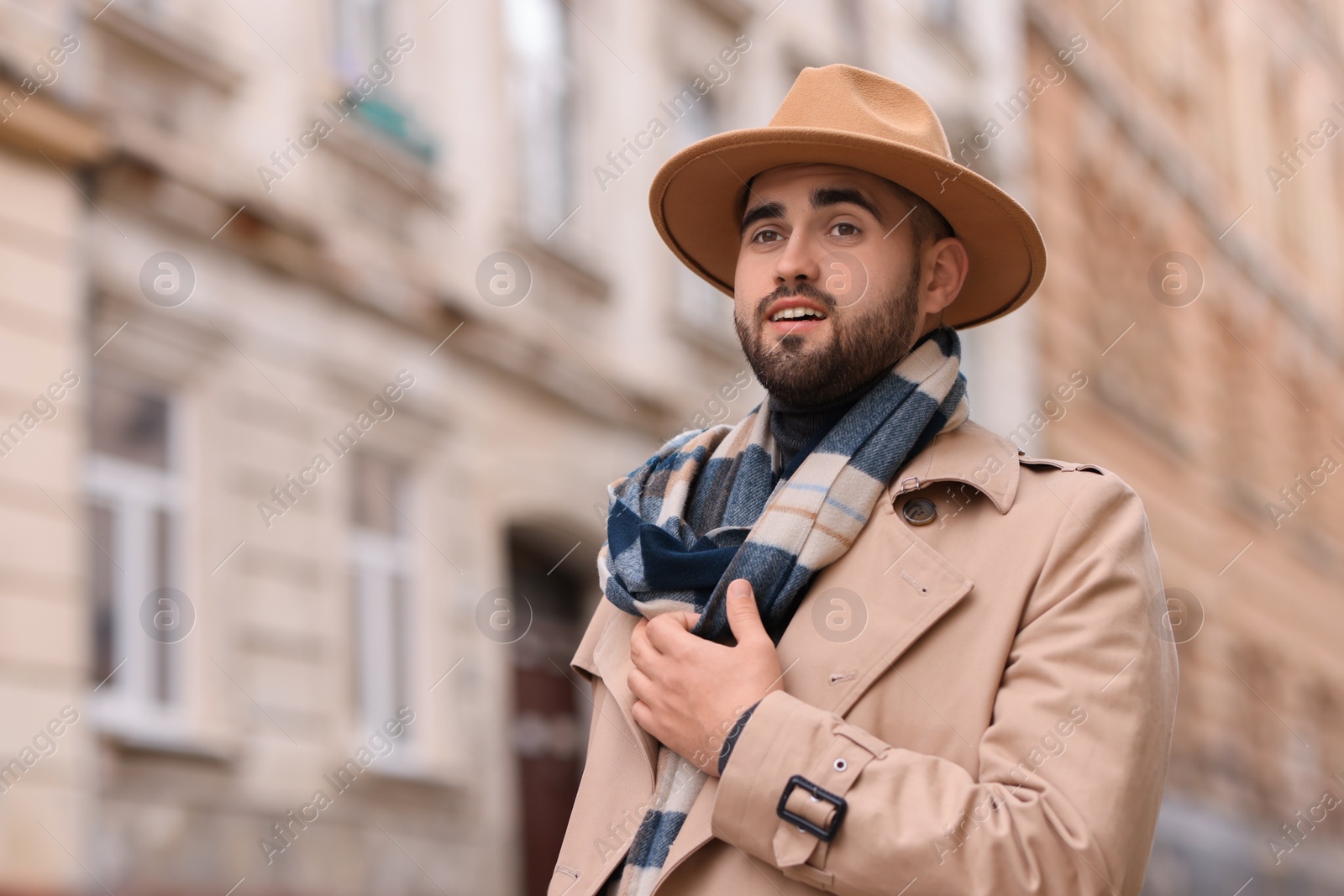 Photo of Handsome man in warm scarf on city street. Space for text