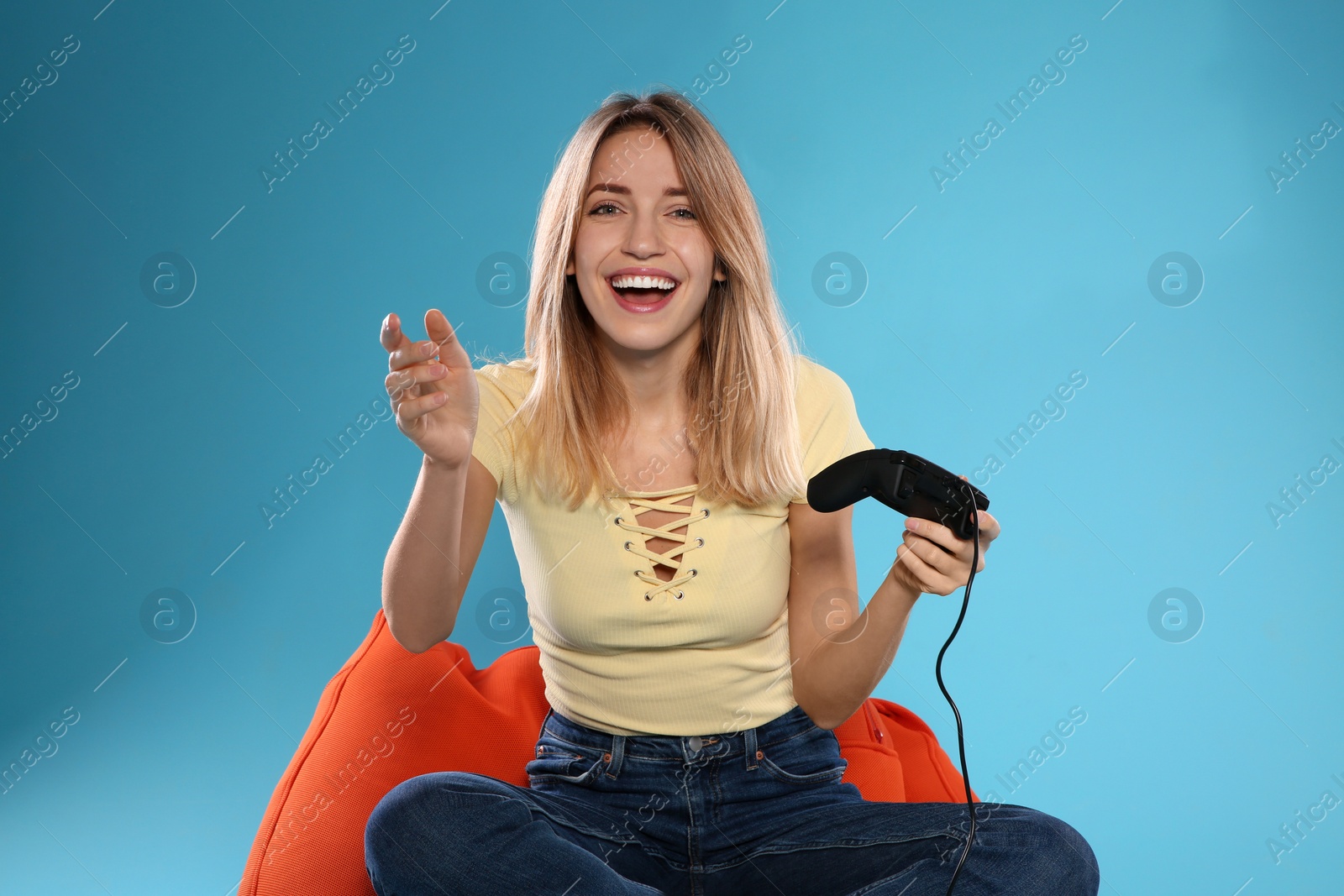 Photo of Emotional young woman playing video games with controller on color background