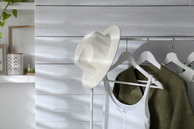 Rack with different stylish clothes and hat in dressing room