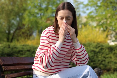 Photo of Woman with napkin suffering from seasonal allergy on bench in park