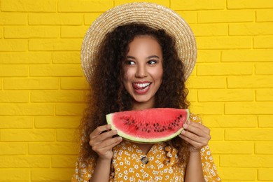 Photo of Beautiful young African-American woman with watermelon near yellow brick wall