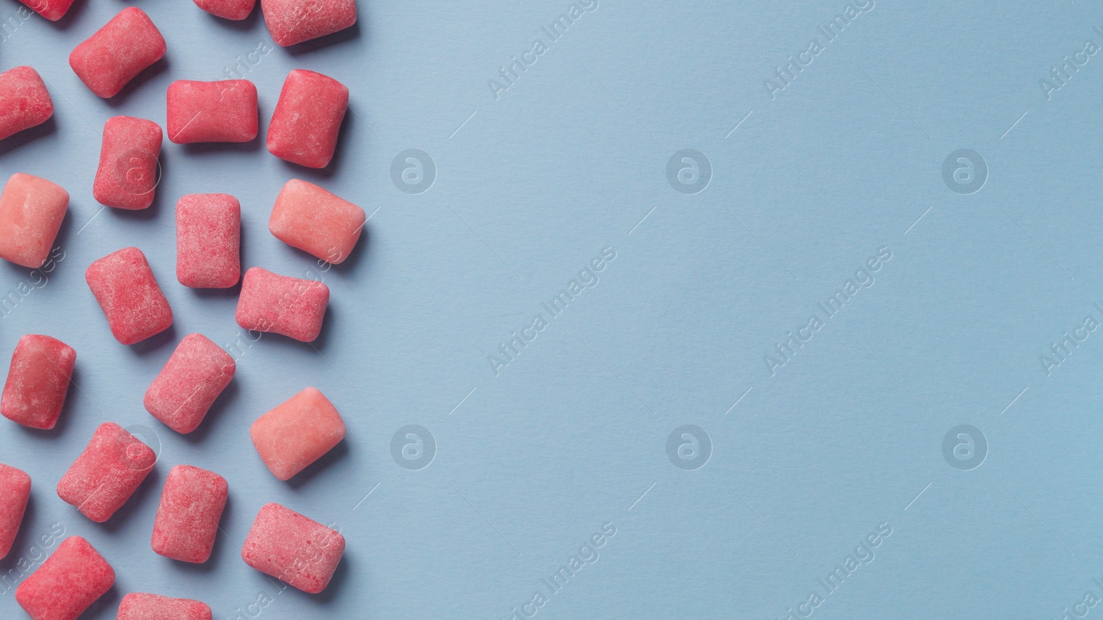 Photo of Many sweet chewing gums on light blue background, flat lay. Space for text