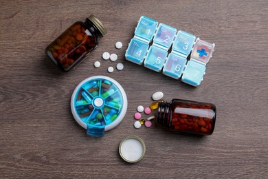 Photo of Pill boxes with medicaments on wooden table, flat lay