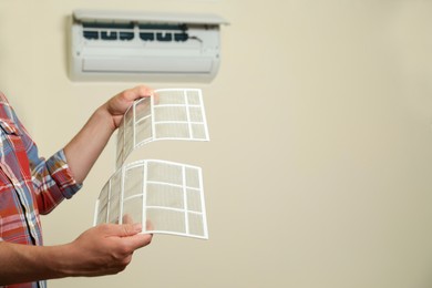 Photo of Man holding filters of air conditioner indoors, closeup