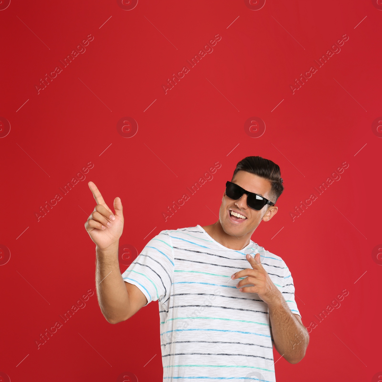 Photo of Handsome man wearing sunglasses on red background
