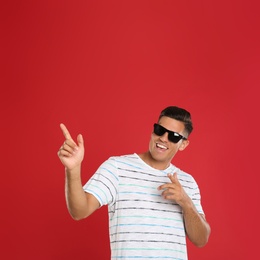 Handsome man wearing sunglasses on red background