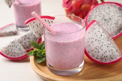 Photo of Delicious pitahaya smoothie, mint and fresh fruits on white wooden table, closeup