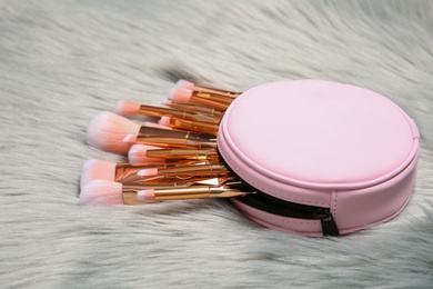 Bag with set of professional makeup brushes on furry fabric