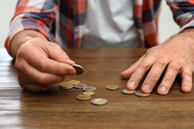 Senior man counting coins at table, closeup