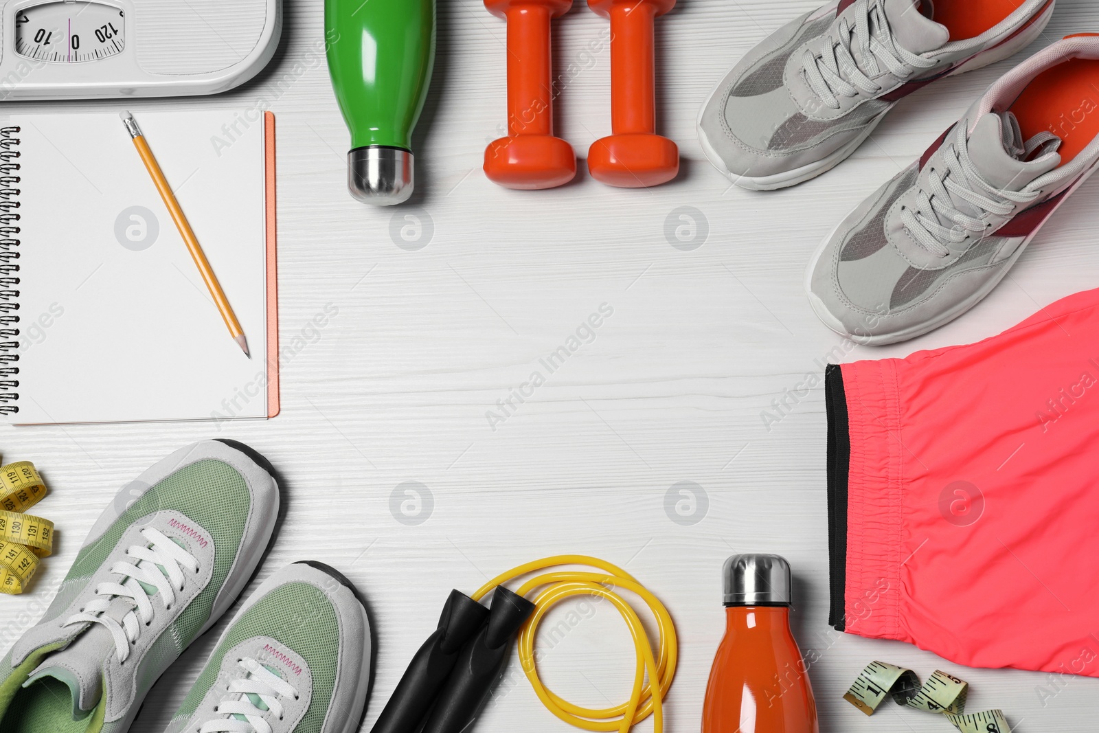 Photo of Notebook, scales and sports equipment on white wooden table, flat lay with space for text. Personal training