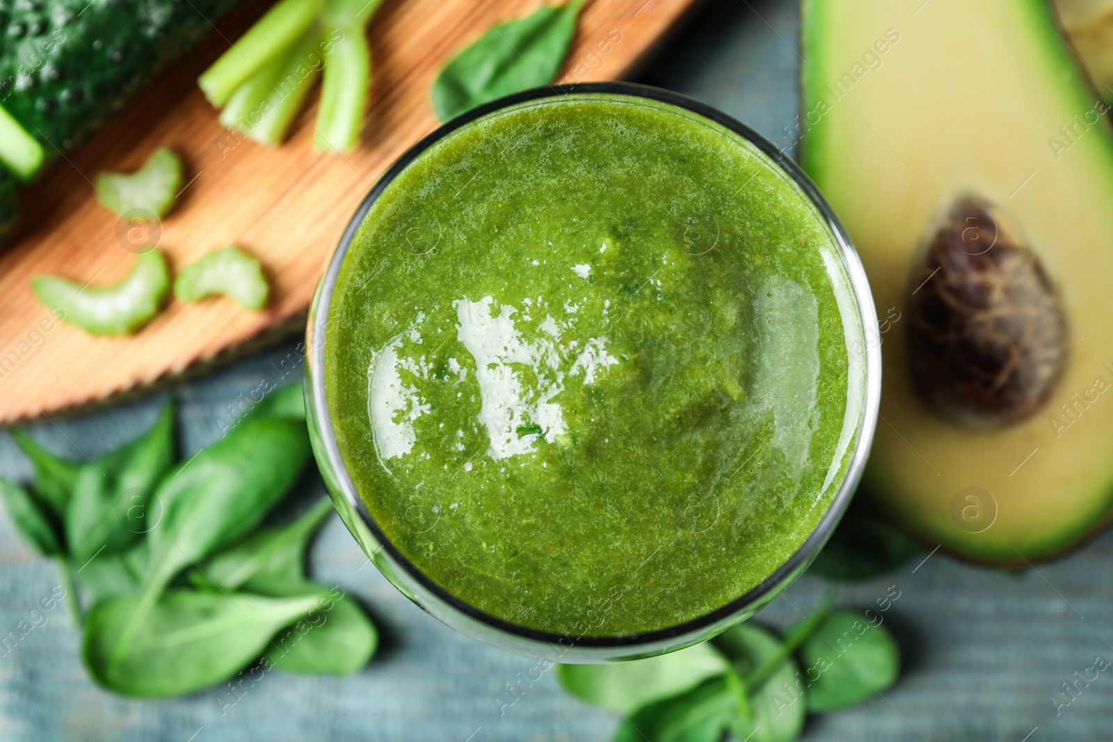 Photo of Delicious fresh green juice on light blue table, flat lay