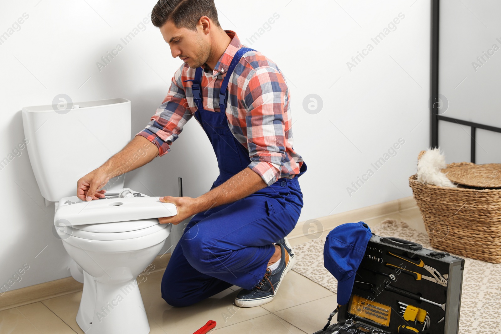 Photo of Professional plumber working with toilet bowl in bathroom