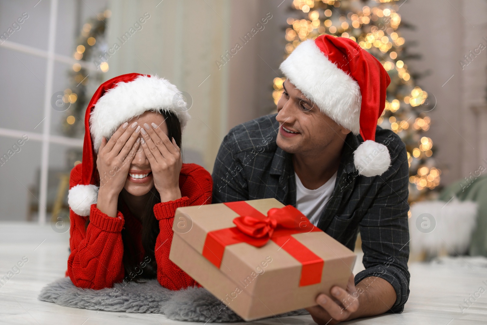 Photo of Man presenting Christmas gift to his girlfriend at home