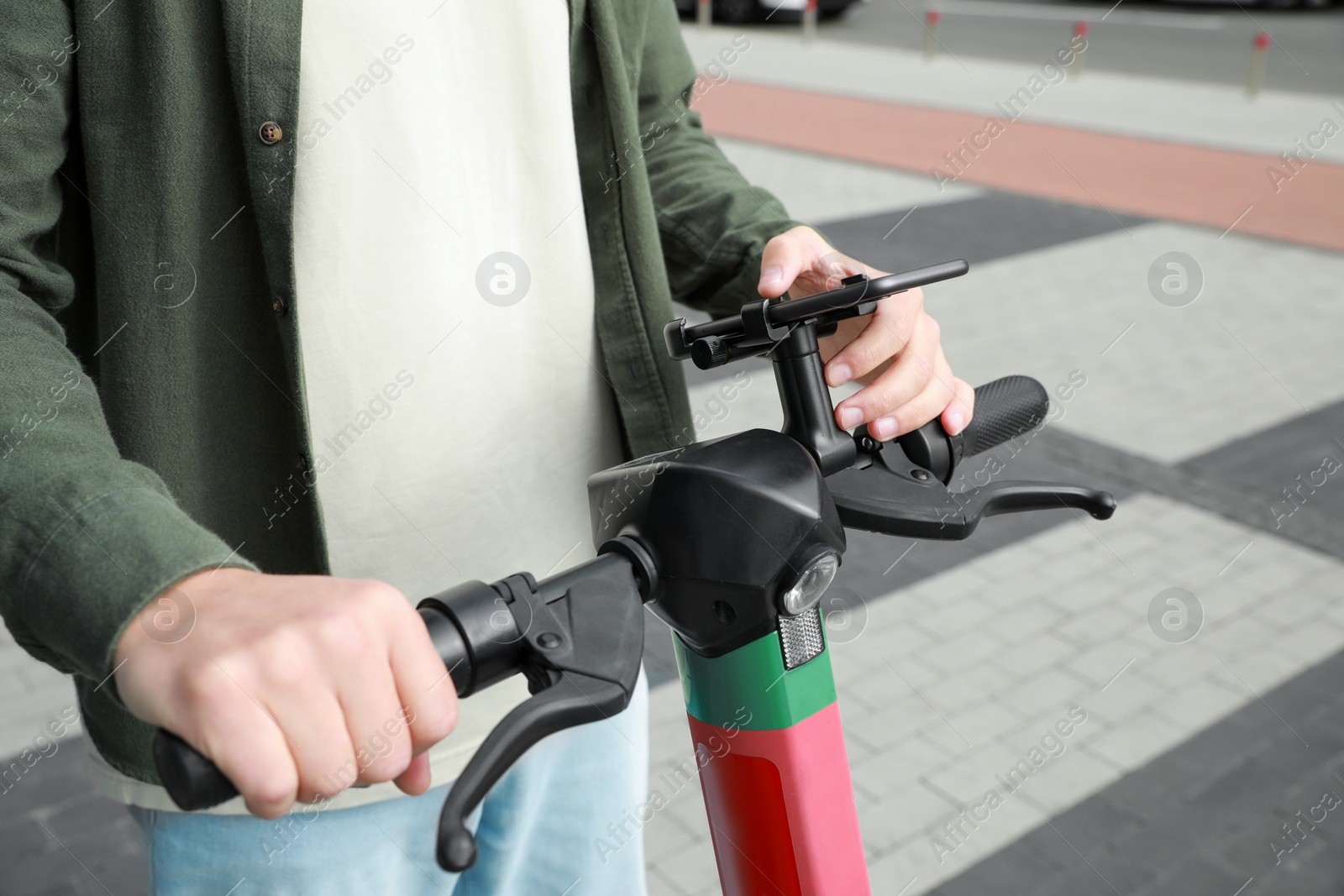 Photo of Man using smartphone to pay and unblock electric kick scooter outdoors, closeup