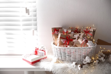 Photo of Set of gifts in basket and Christmas decor on window sill indoors. Advent calendar