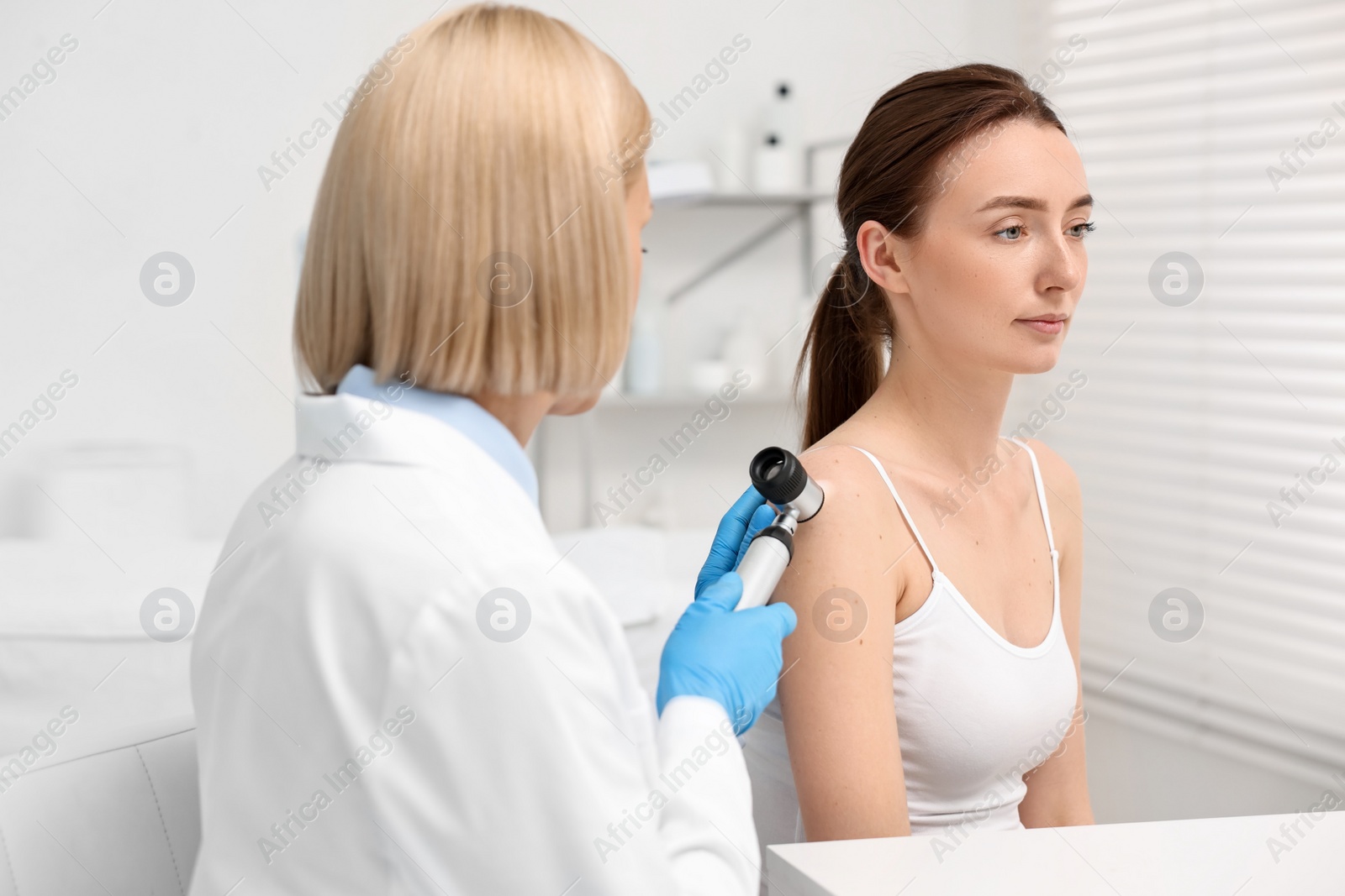 Photo of Dermatologist with dermatoscope examining patient in clinic