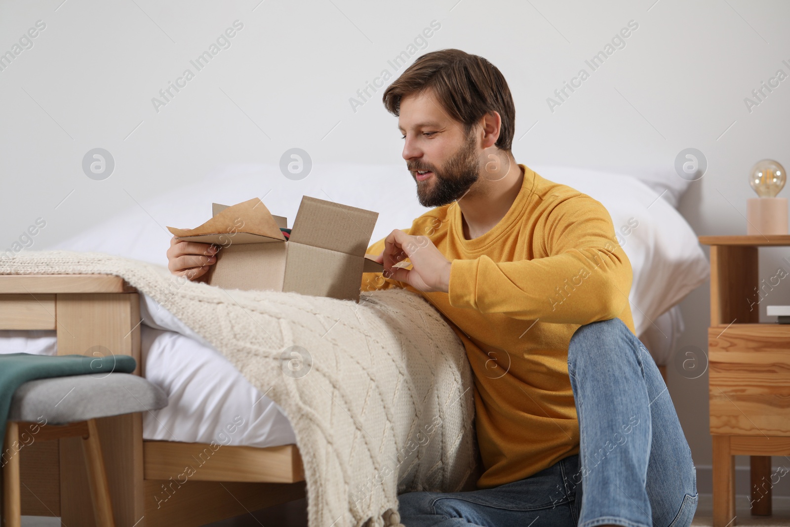 Photo of Happy man opening parcel at home. Internet shopping