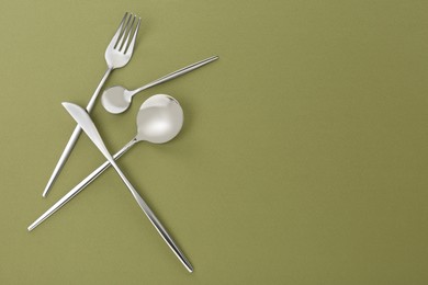 Photo of Fork, knife and spoons on green background, flat lay with space for text. Stylish cutlery set