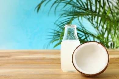 Composition with bottle of coconut water on wooden table against blue background. Space for text