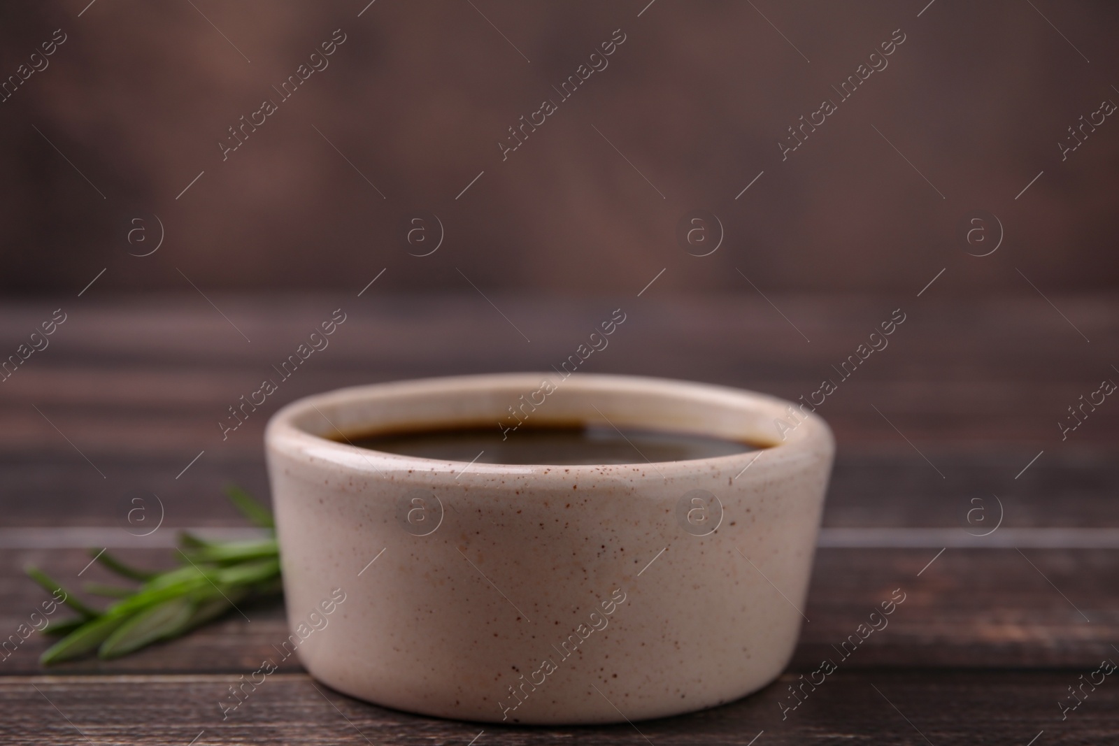 Photo of Bowl with balsamic vinegar on wooden table